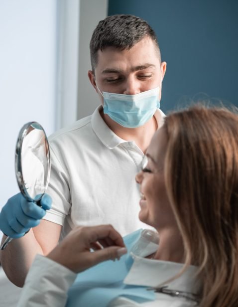 In a dental clinic, the patient rests in a chair, looks in the mirror at the result of work and dental treatment, relying on the experience and qualifications of the doctor who performs the treatment. High quality photo